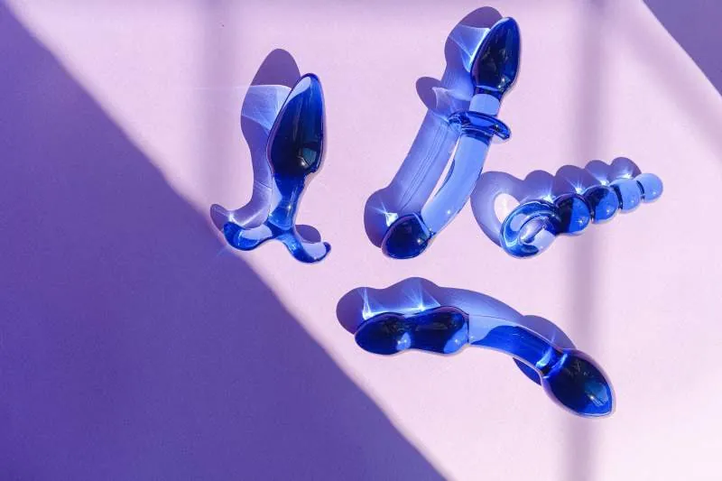 Vier blaue Glas-Sextoys auf lilafarbenem Hintergrund
