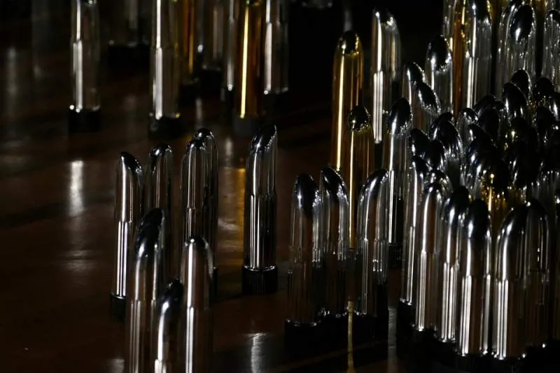 Reihen glänzender Glas- und Metallobjekte auf spiegelnder Fläche